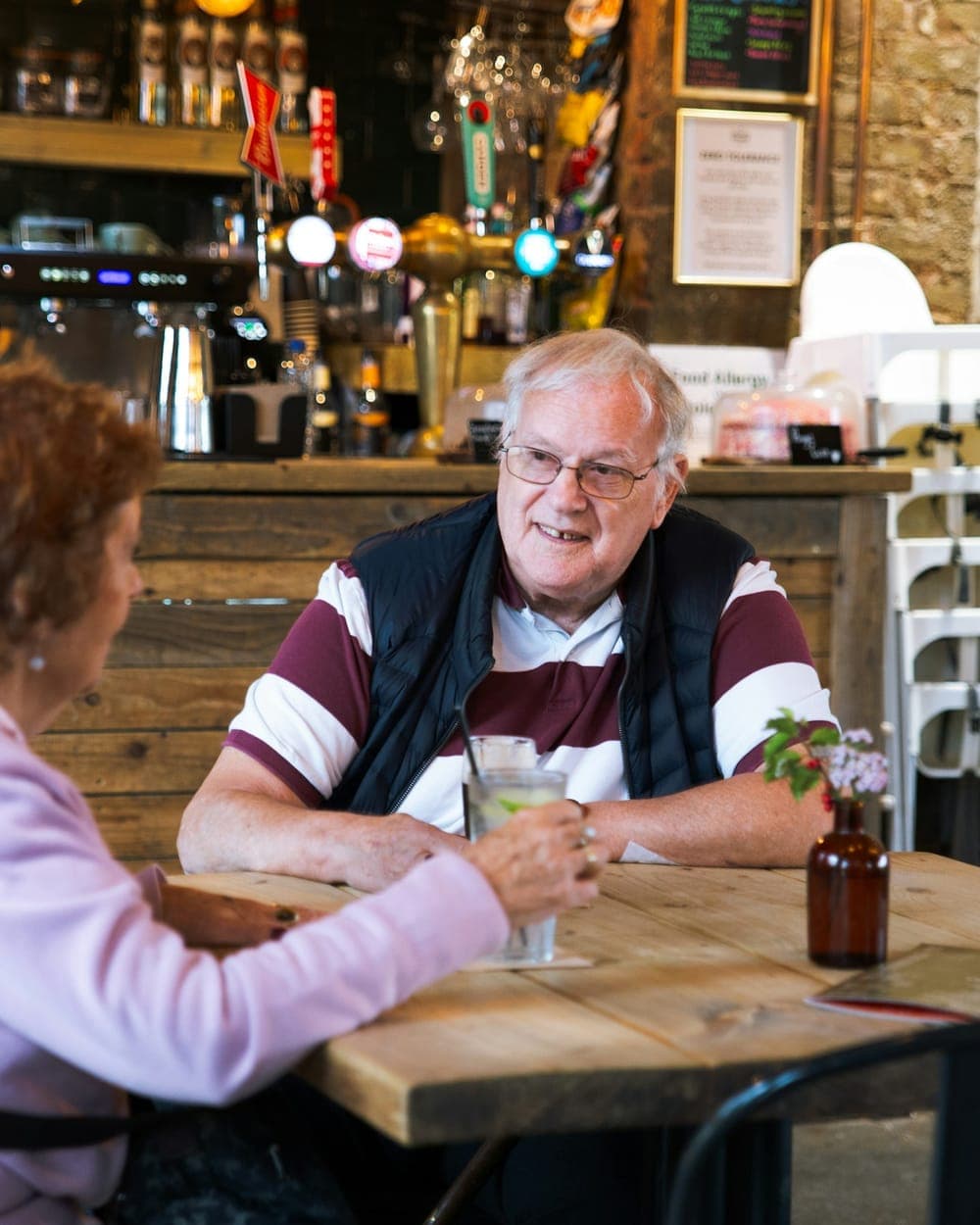An older couple sitting together at a pub table with their drinks.